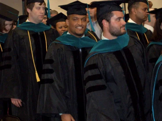 Graduates in doctoral regalia with teal hoods at a graduation ceremony — the one photograph published on Reed Physical Therapy's own website.